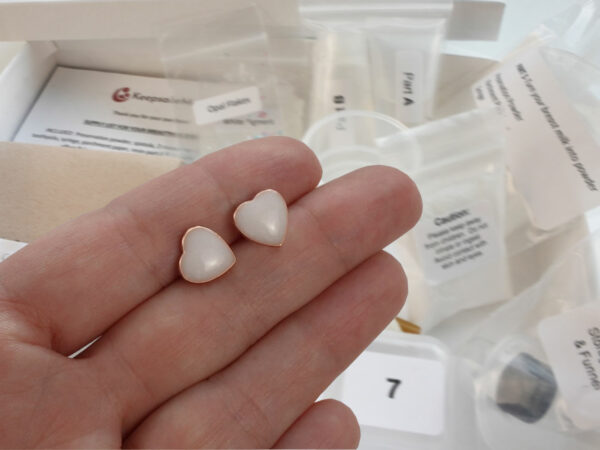 DIY kit breastmilk jewelry heart earrings shown on a hand for DIY kit from KeepsakeMom on open diy kit box background