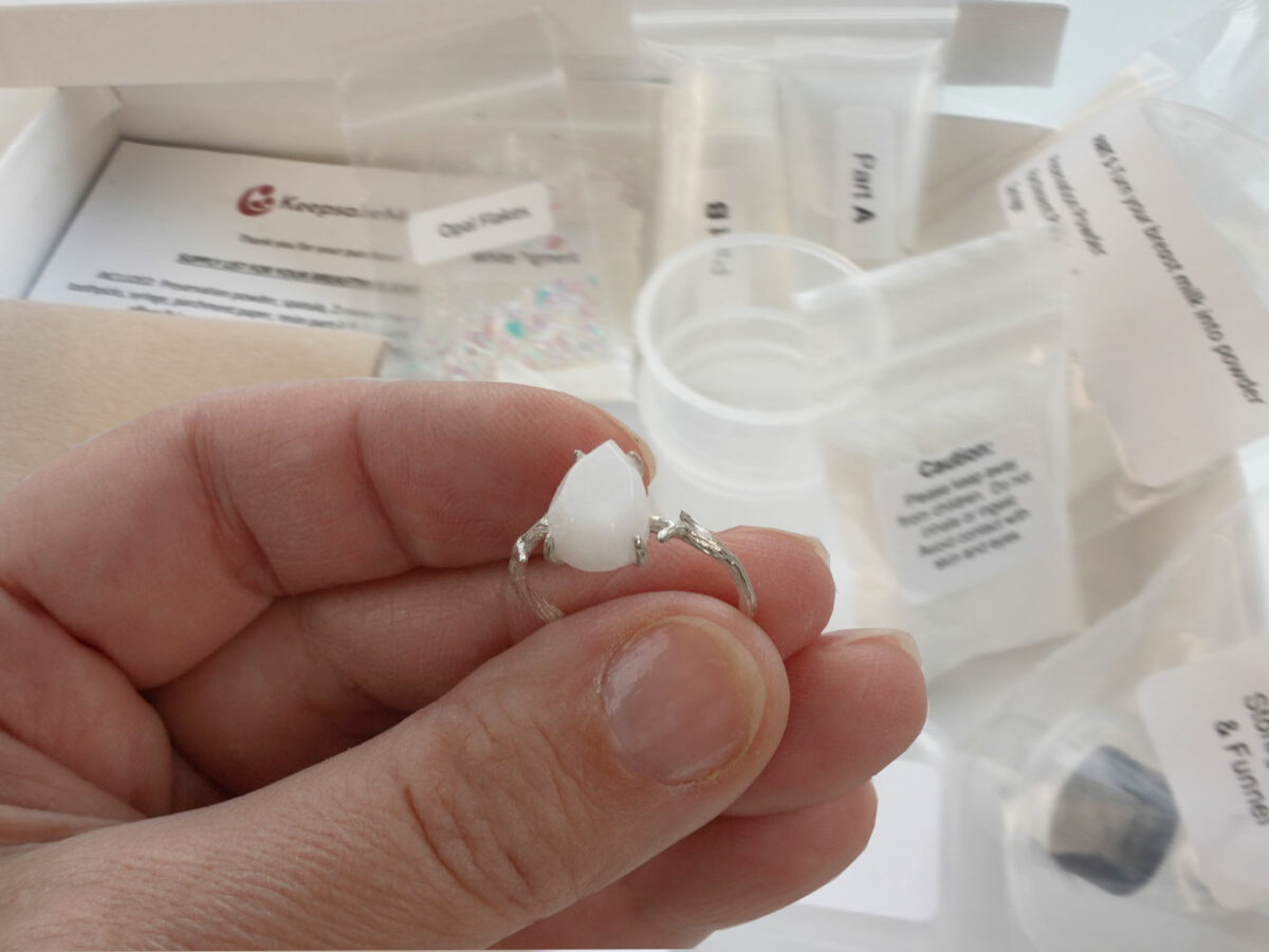 DIY kit breastmilk jewelry branch silver ring shown on a hand for DIY kit from KeepsakeMom on open kit box background