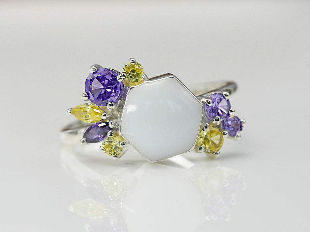 breastmilk ring in hexagon shape milk and honey with different purple and yellow birth month color crystals on each side from keepsakemom