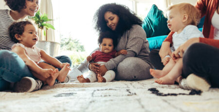 A group of moms sitting on the floor with their babies.