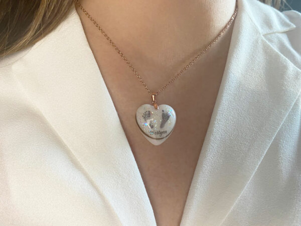 breastmilk jewelry necklace from KeepsakeMom heart with baby prints and name and hair on a model from KeepsakeMom