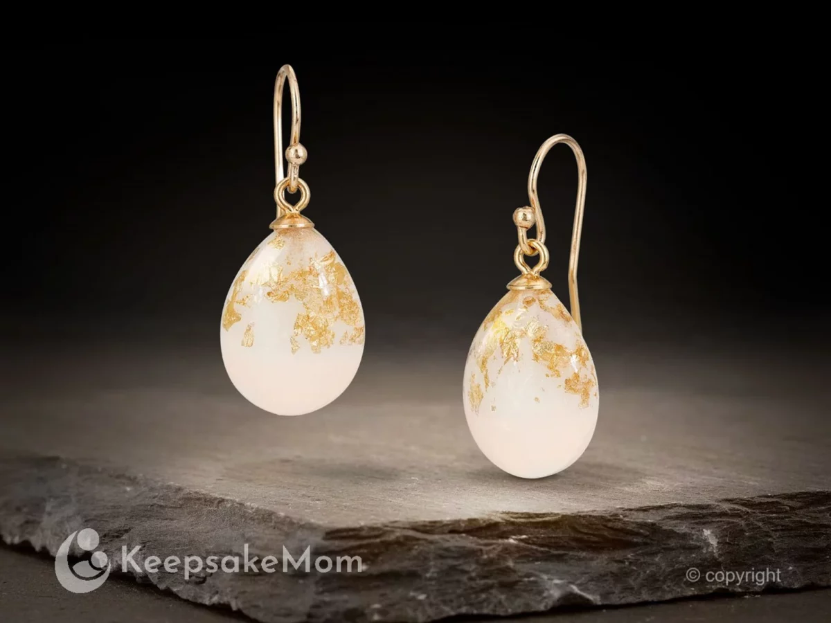 breastmilk jewelry drop shaped earrings on a dark background hanging with gold flakes and gold hooks from KeepsakeMom