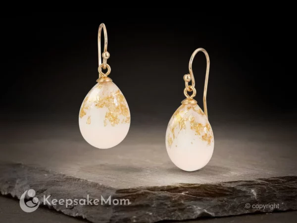 breastmilk jewelry drop shaped earrings on a dark background hanging with gold flakes and gold hooks from KeepsakeMom