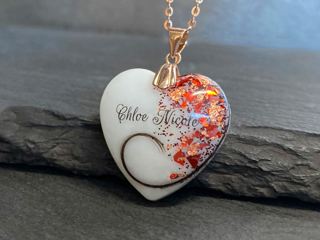Breastmilk jewelry heart necklace with garnet red January birth month color flakes and baby's name and lock of hair swirl from KeepsakeMom with rose gold chain and bail