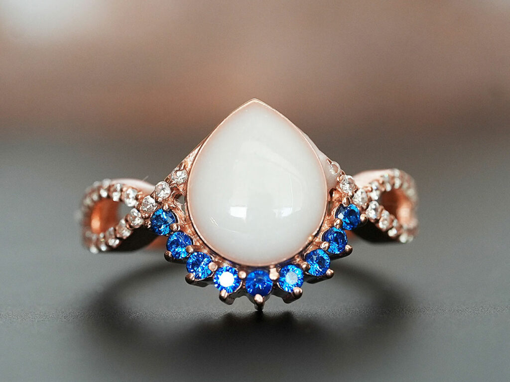 breastmilk jewelry rose gold ring with blue tanzanite December birth month color crystals around teardrop breastmilk stone from KeepsakeMom