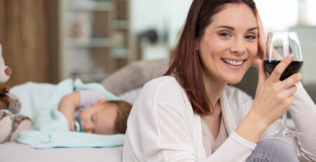 Mom holding a glass of wine while baby naps