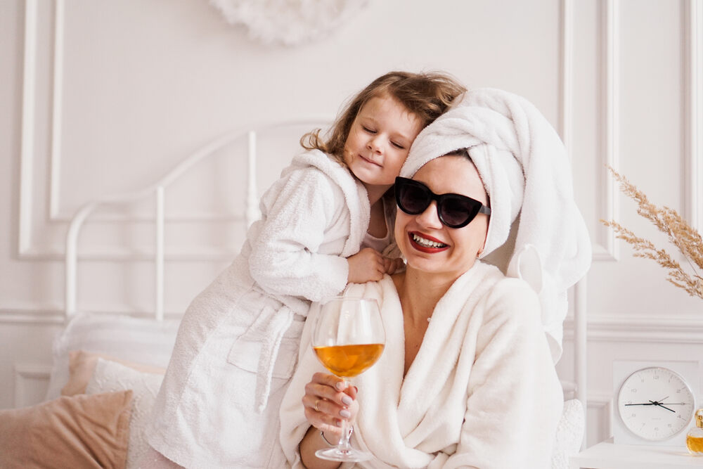 Mom in spa robe drinking a glass of wine in bed