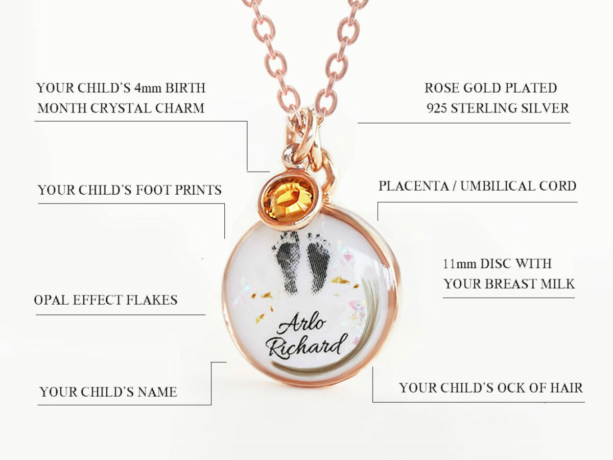 breast milk disc round shaped necklace with baby foot prints, lock of hair, placenta specks, opal flakes and orange dangle in rose gold setting on white background describing features diagram from keepsakemom