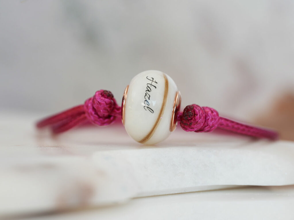 breastmilk jewelry ruby red birth month color bracelet cord with a breastmilk bead with lock of hair and name from KeepsakeMom