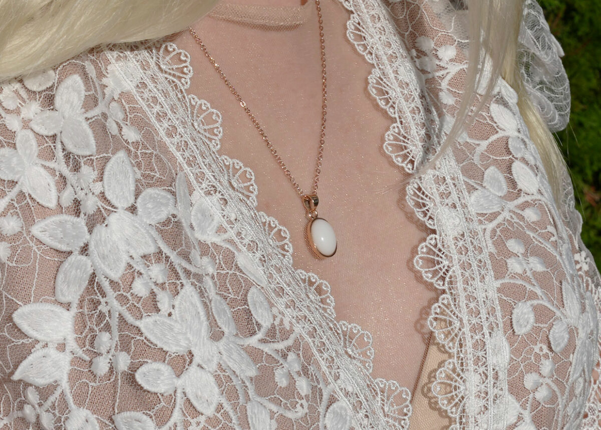 breastmilk jewelry model in white dress wearing oval necklace from KeepsakeMom