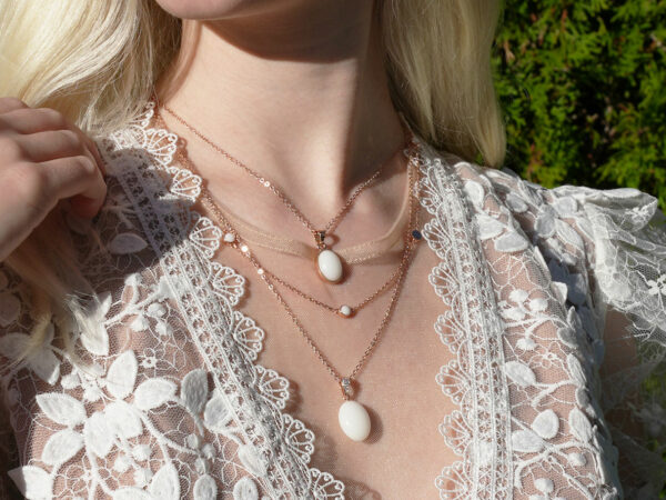 breastmilk jewelry model in white dress wearing layered breastmilk necklaces from KeepsakeMom