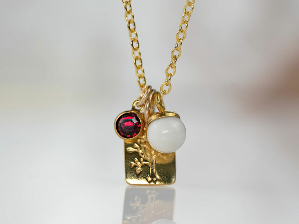 breastmilk jewelry charm necklace with garnet red January birth month color dangle crystal and tree on the metal with breastmilk pearl charm from KeepsakeMom