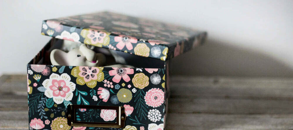 A floral printed baby keepsake box with a special infant toy inside