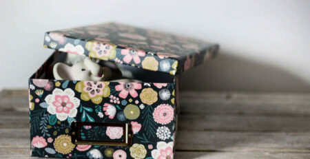 A floral printed baby keepsake box with a special infant toy inside
