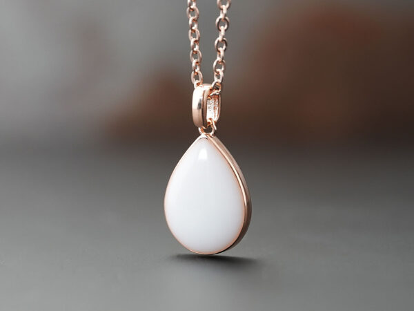 breastmilk jewelry teardrop pear shaped necklace in rose gold on brown background from keepsakemom