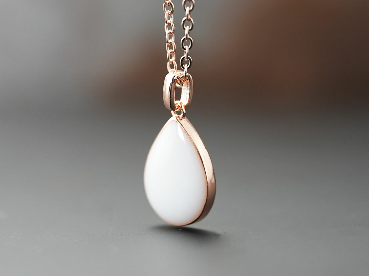 breastmilk jewelry teardrop pear shaped necklace in rose gold on brown background from keepsakemom
