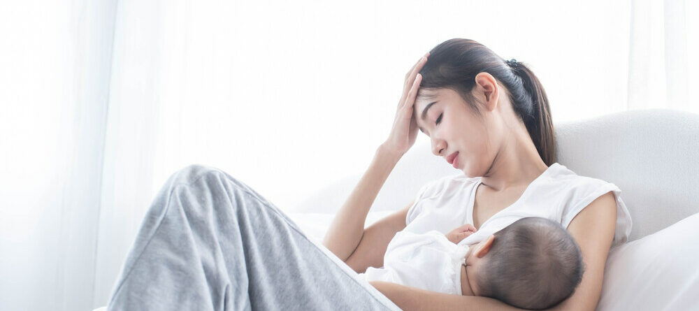 Stressed mom on bed breastfeeding newborn