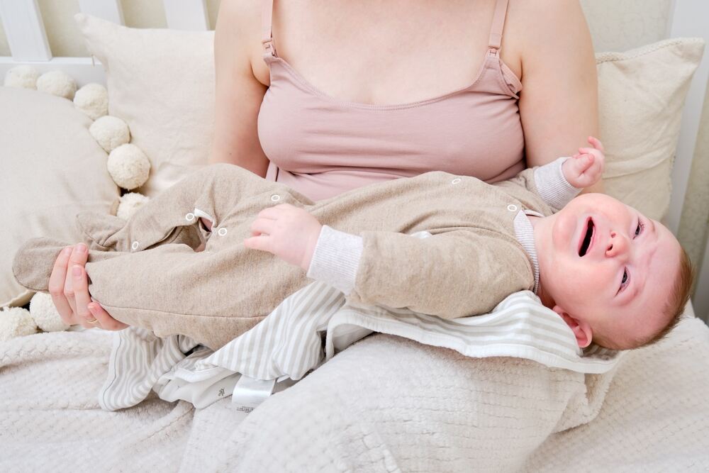 Fussy infant in mother's lap after trying to breastfeed
