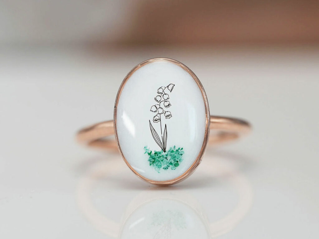 breast milk ring oval shaped with flower outline in the milk stone with green gems from keepsakemom