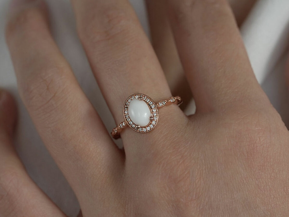 breastmilk jewelry ring oval stone fine band with crystals around the stone and the band fine ring rose gold KeepsakeMom model hand