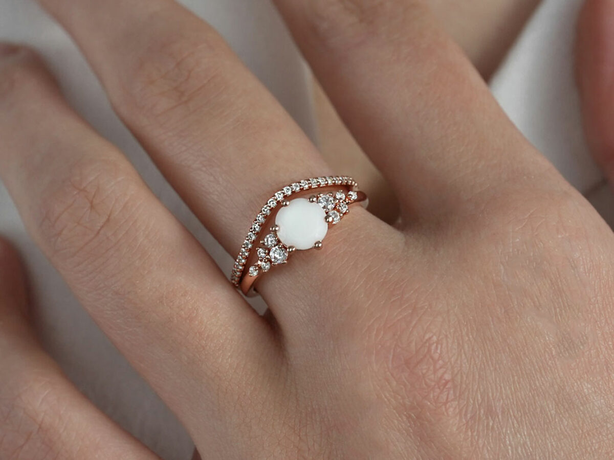 breastmilk jewelry silver ring set diamond shaped milk stone and five gems on each side purple birth month colors clear diamonds from KeepsakeMom and top add-on ring in a wave shape on a model hand