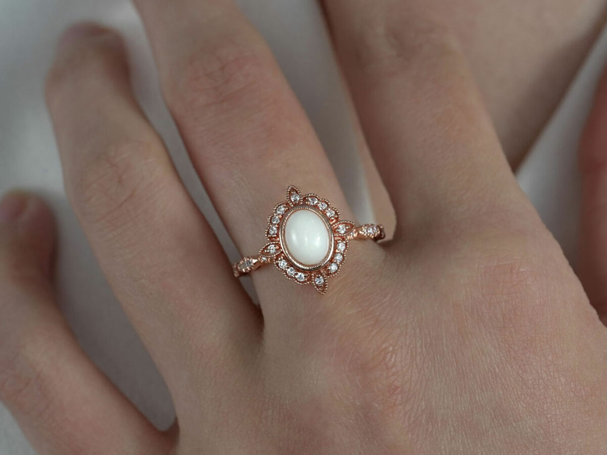 breast milk ring in art deco style with oval milk central stone in rose gold setting from keepsakemom on a model hand