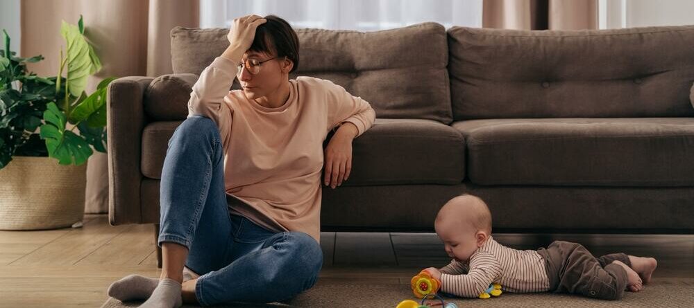 Mom with headache sitting in front of couch