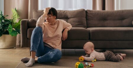 Mom with headache sitting in front of couch