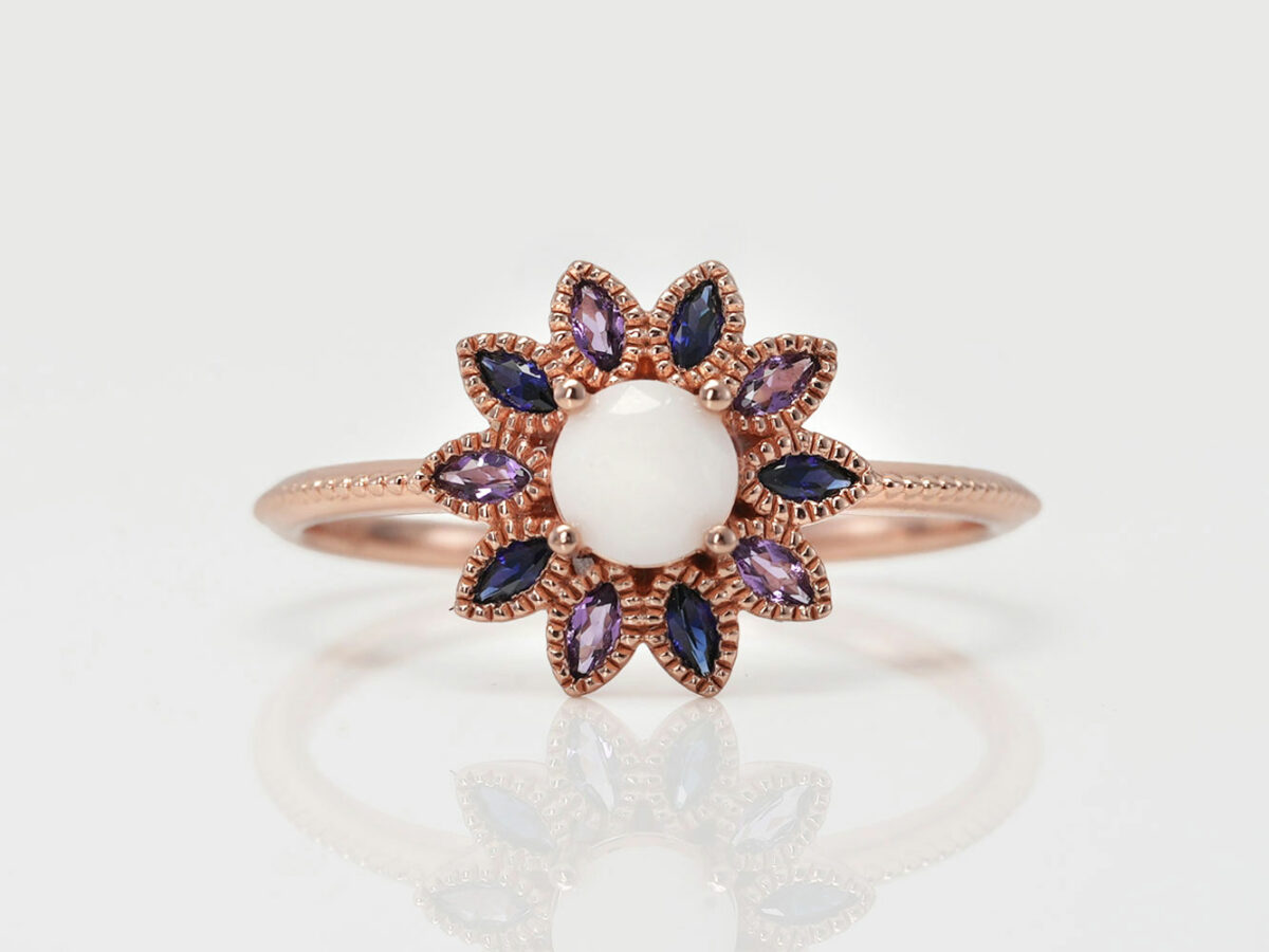 breast milk ring flower shape with purple and blue crystals around the diamond shaped central milk stone from keepsakemom on white background