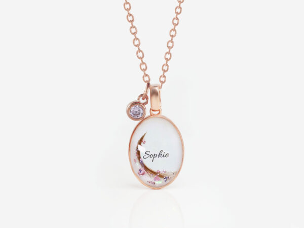 breastmilk jewelry oval simple necklace from keepsakemom in rose gold setting on white background with flakes, hair, name and tiny purple charm
