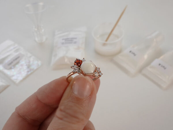 DIY kit breastmilk jewelry rose gold ring shown on a hand for DIY kit from KeepsakeMom on open kit box background