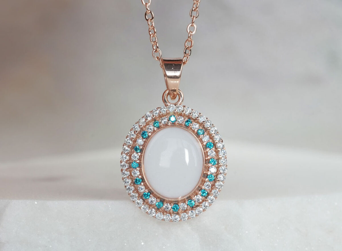 breastrmilk jewelry oval necklace with double halo of birth month color crystals from KeepsakeMom in rose gold with clear and aqua blue crystals alternating