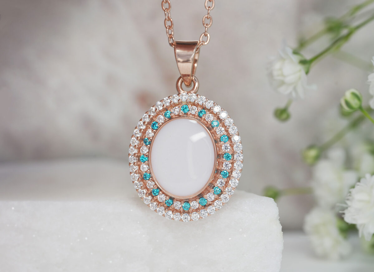 breastrmilk jewelry oval necklace with double halo of birth month color crystals from KeepsakeMom in rose gold with clear and aqua blue crystals alternating
