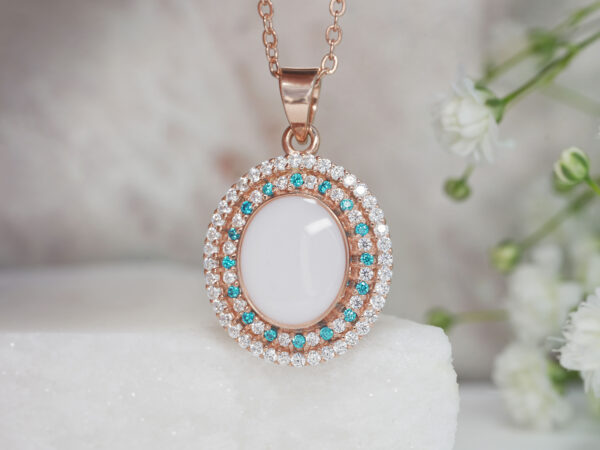 breastrmilk jewelry oval necklace with double halo of birth month color crystals from KeepsakeMom in rose gold with clear and aqua blue crystals alternating