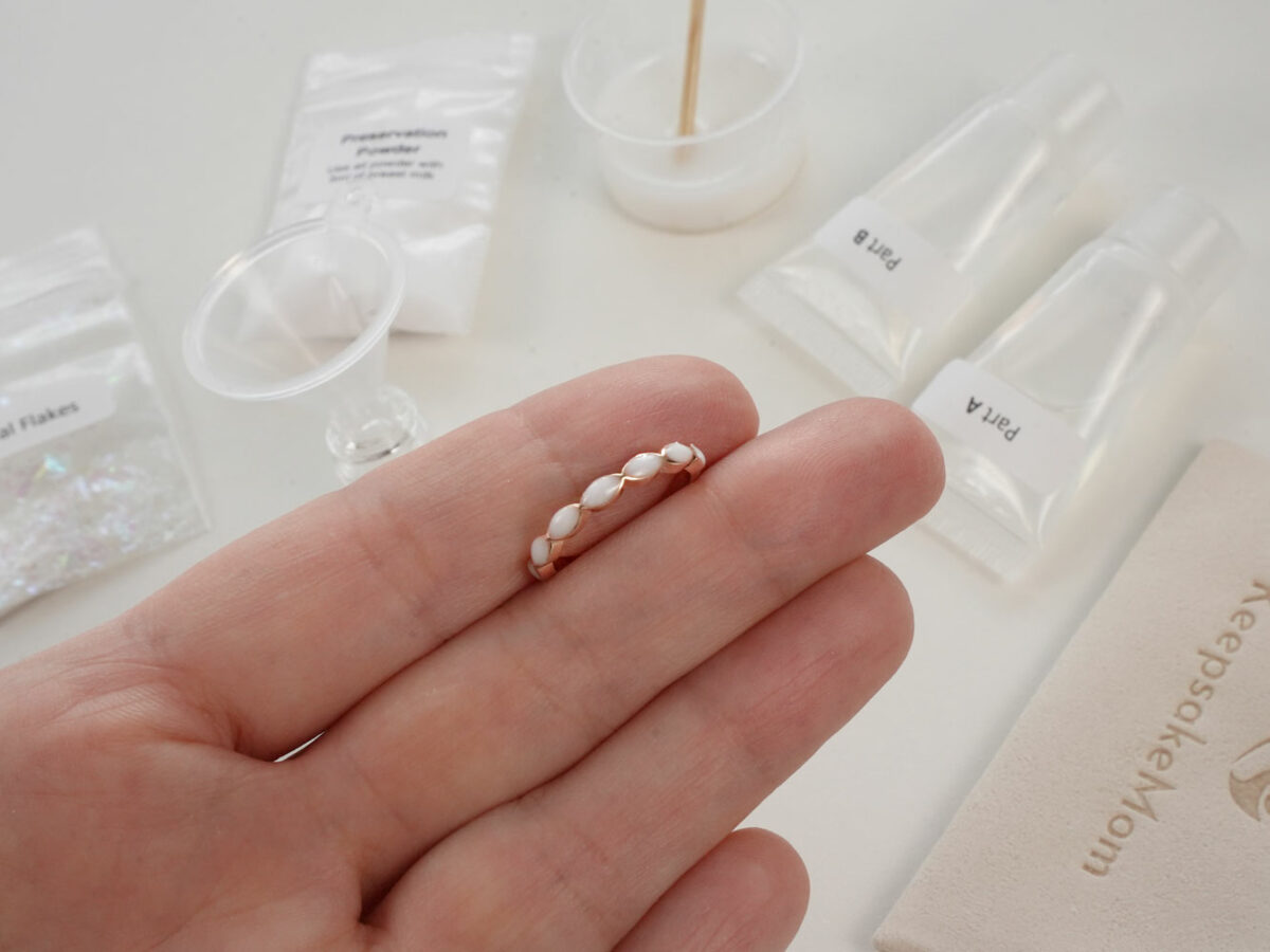 DIY kit breastmilk jewelry rose gold fine band marquise style ring shown on a hand for DIY kit from KeepsakeMom on open kit box background