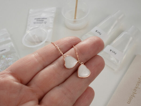 DIY kit breastmilk jewelry rose gold two hearts necklace shown on a hand for DIY kit from KeepsakeMom on open kit box background