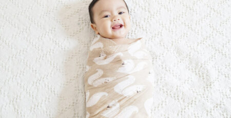 Smiling swaddled baby on a bed