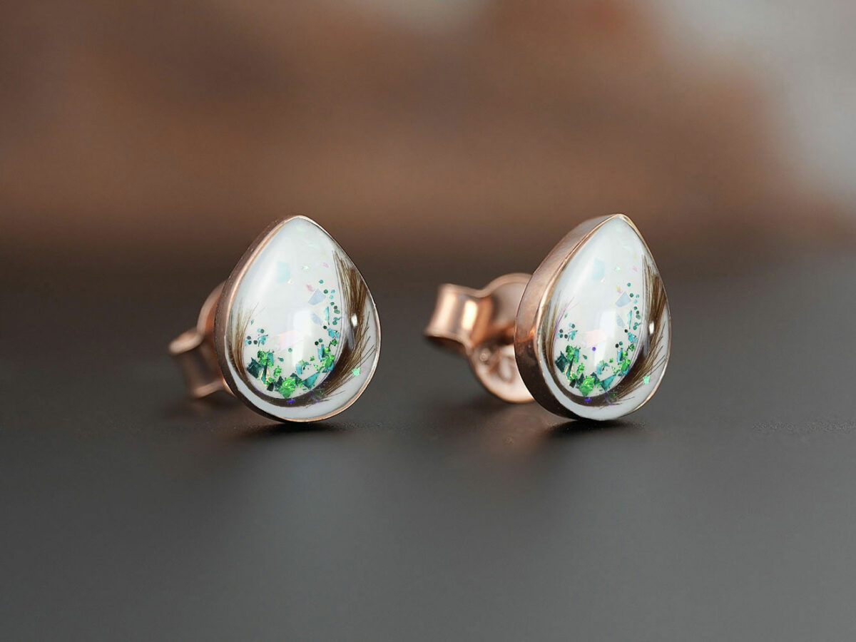 breastmilk pear teardrop shaped studded earrings from KeepsakeMom sterling silver on brown background with green flakes and locks of hair