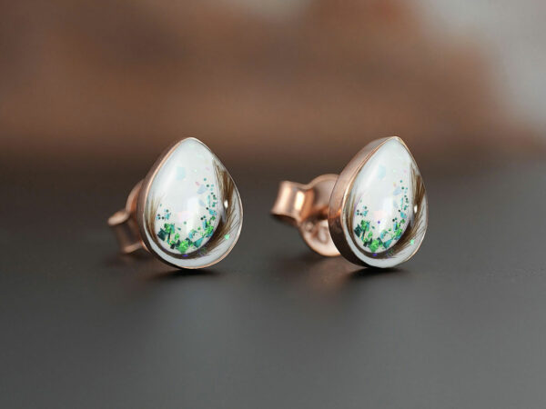 breastmilk pear teardrop shaped studded earrings from KeepsakeMom sterling silver on brown background with green flakes and locks of hair