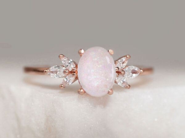 breastmilk ring burst of love oval with three crystals on each side of the pink milk oval stone from KeepsakeMom with crushed opal gems in the milk stone