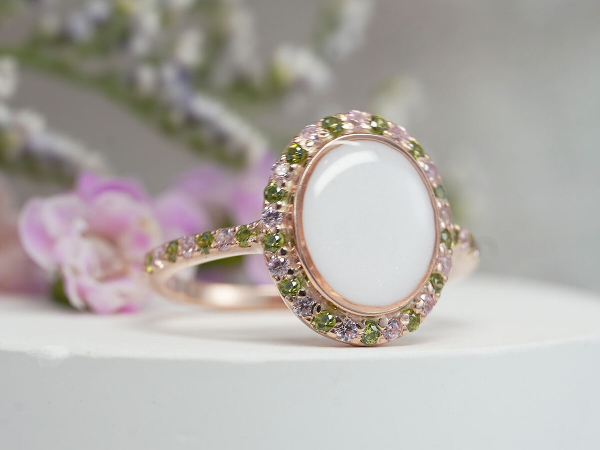 breastmilk ring with oval shaped central breastmilk stone with alternating green and light pink tourmaline October crystals or gems as halo around the stone and around the ring band from keepsakemom in rose gold setting