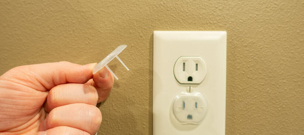 Parent baby-proofing their home by covering electrical outlet