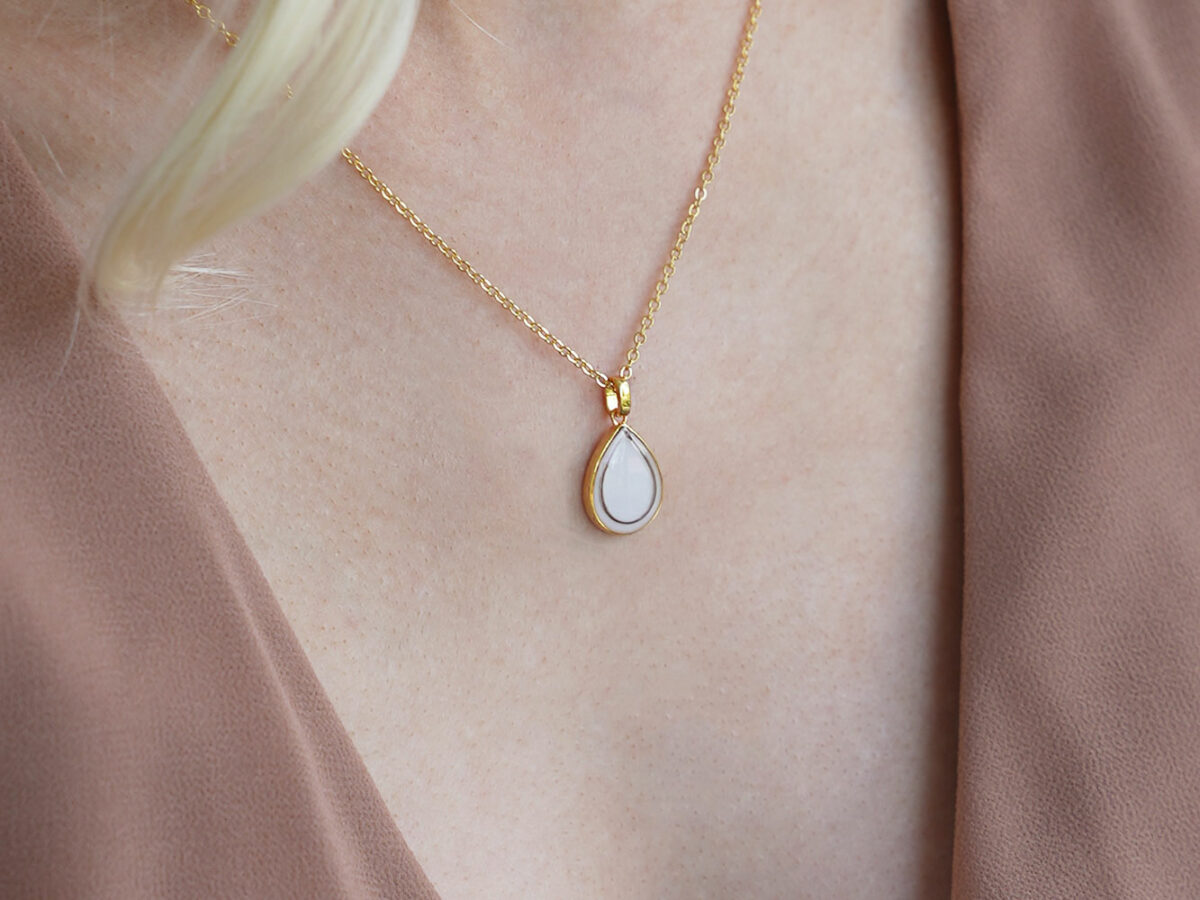 breastmilk jewelry teardrop pear shaped necklace in gold with lock of hair on a blonde model from keepsakemom