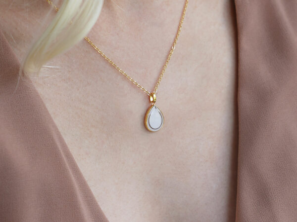 breastmilk jewelry teardrop pear shaped necklace in gold with lock of hair on a blonde model from keepsakemom