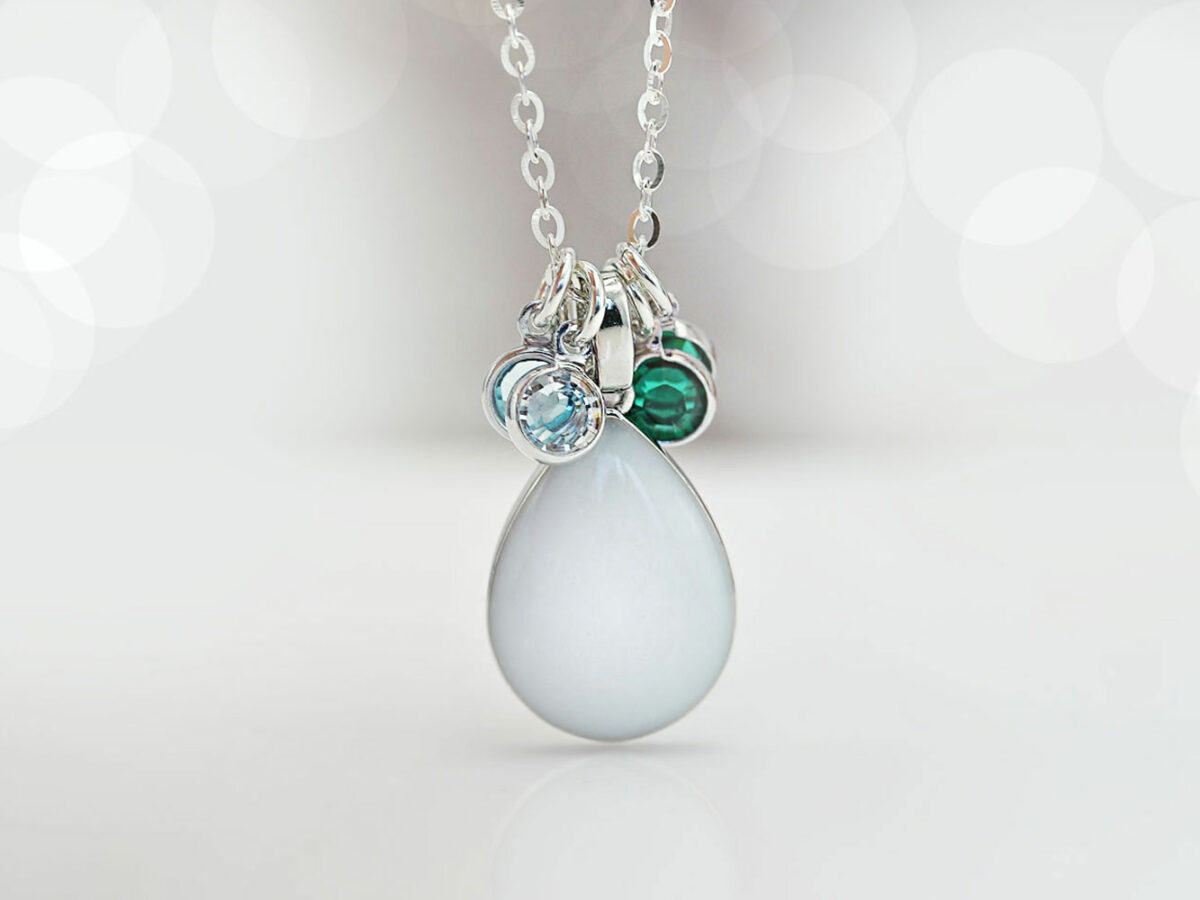 breastmilk jewelry teardrop pear shaped necklace in sterling silver on white background with 4 charms green and light blue from keepsakemom