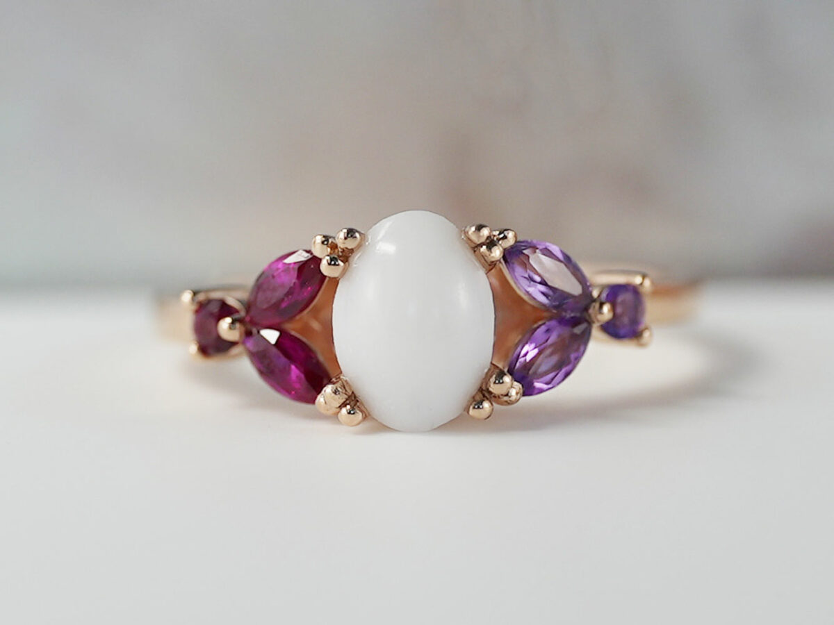 breast milk ring with oval stone and ruby and amethyst crystals or gems on each side in rose gold setting from KeepsakeMom