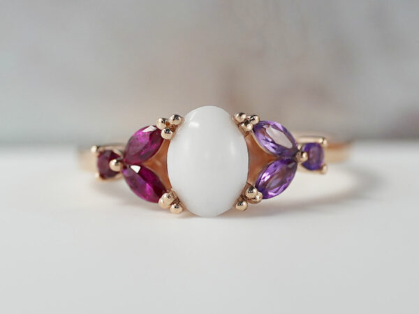 breast milk ring with oval stone and ruby and amethyst crystals or gems on each side in rose gold setting from KeepsakeMom