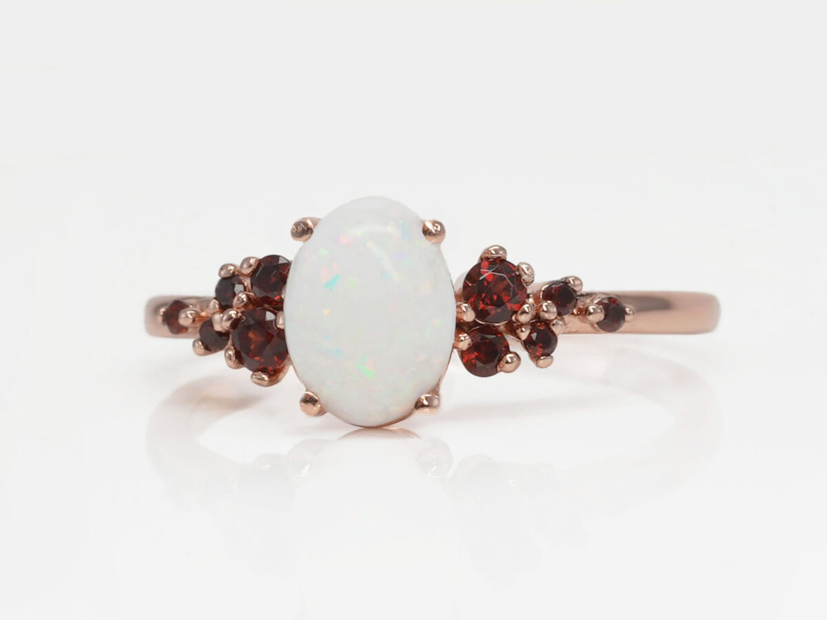 breast milk ring on a white background in rose gold and garnet red crystals on a side and central milk stone from keepsakemom