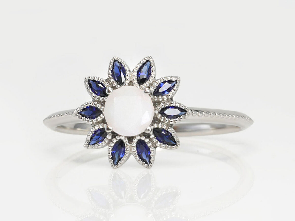 breast milk silver ring flower shape with blue crystals around the diamond shaped central milk stone from keepsakemom on white background