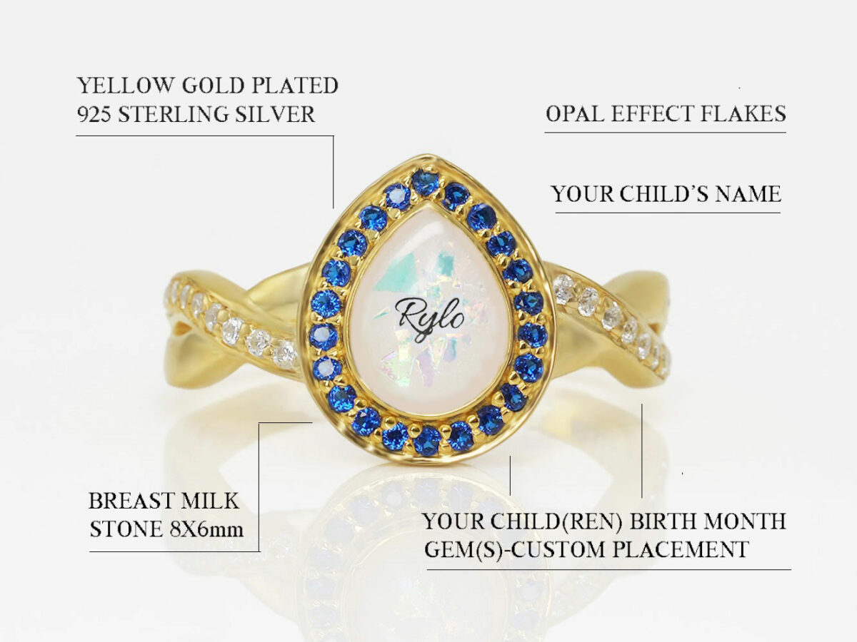 breastmilk sterling silver ring gold plated with opal flakes and name inside breastmilk drop shaped stone and blue sapphire crystals around with clear crystals on the thick band diagram describing features on white background from keepsakemom